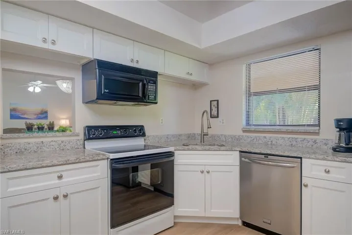 Kitchen with sink, white cabinetry, electric range oven, light stone countertops, and stainless steel dishwasher
