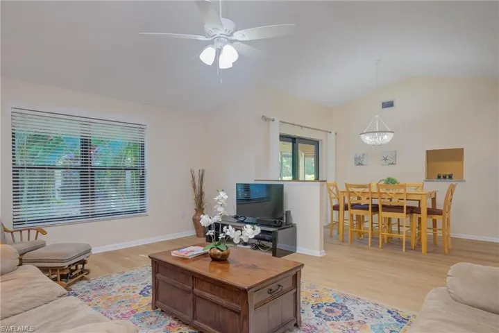 Living room with ceiling fan, lofted ceiling, and light hardwood / wood-style floors