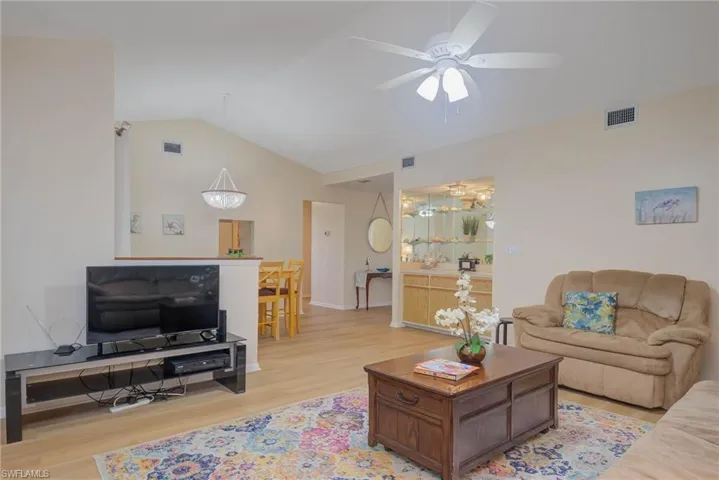 Living room featuring light hardwood / wood-style flooring, vaulted ceiling, and ceiling fan