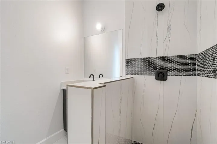 Bathroom featuring vanity and a marble finish shower