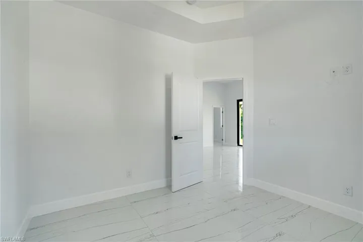 Unfurnished room featuring light marble finish floors and a high ceiling
