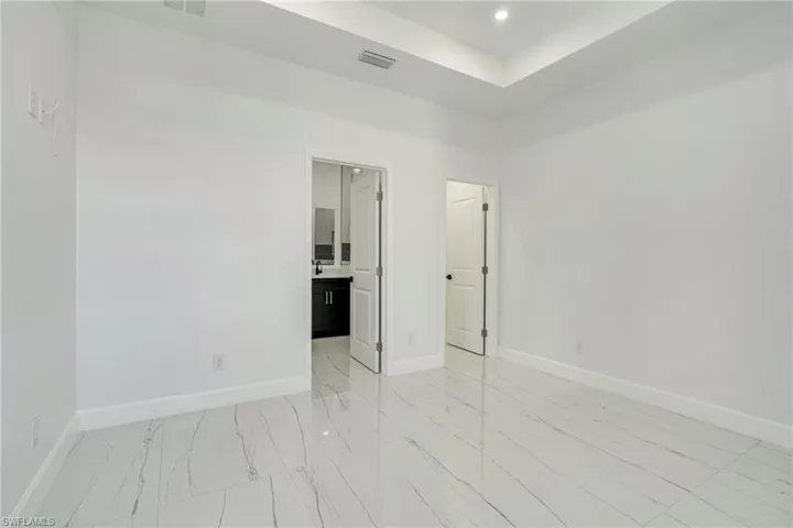 Unfurnished room featuring recessed lighting, light marble finish flooring, and a tray ceiling