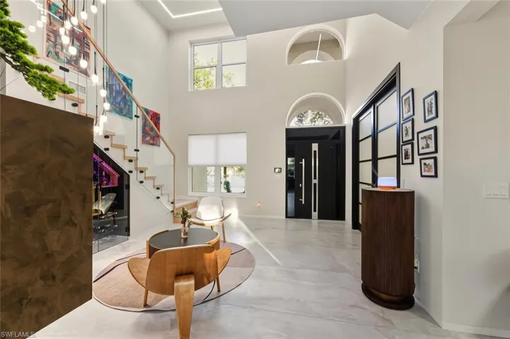 Foyer entrance featuring concrete floors, stairway, and a high ceiling