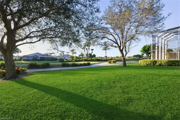 View of grassy yard featuring a lanai and a sunroom
