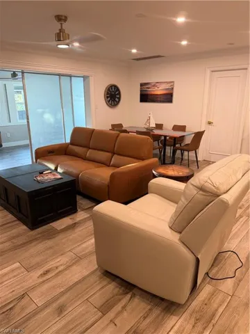 Living area with light wood-style flooring, ceiling fan, and recessed lighting