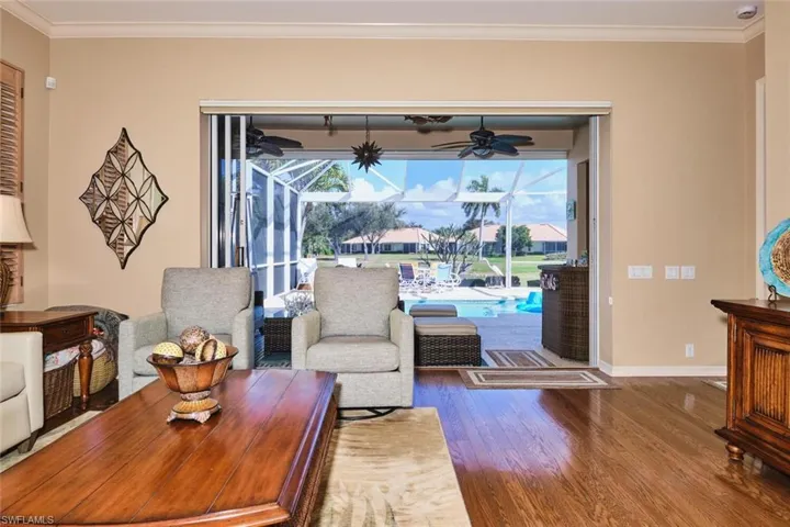 Living area with ornamental molding, a sunroom, wood finished floors, and ceiling fan