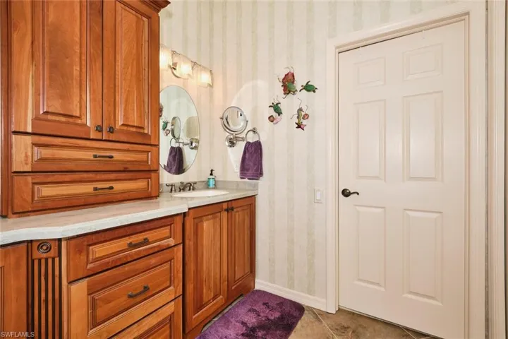 Bathroom featuring wallpapered walls, vanity, and light tile patterned floors
