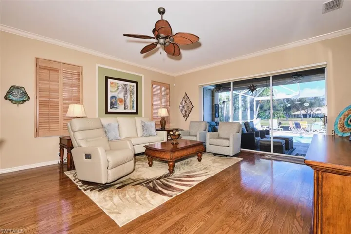 Living room with a ceiling fan, ornamental molding, and wood finished floors