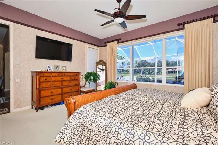 Carpeted bedroom with a ceiling fan and baseboards