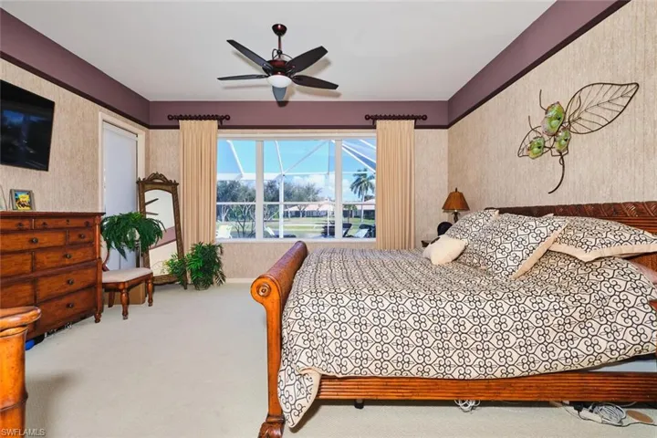 Carpeted bedroom with wallpapered walls and ceiling fan