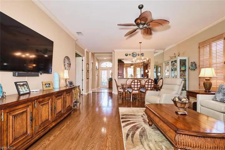 Living area featuring crown molding, light wood finished floors, a ceiling fan, and hanging lights