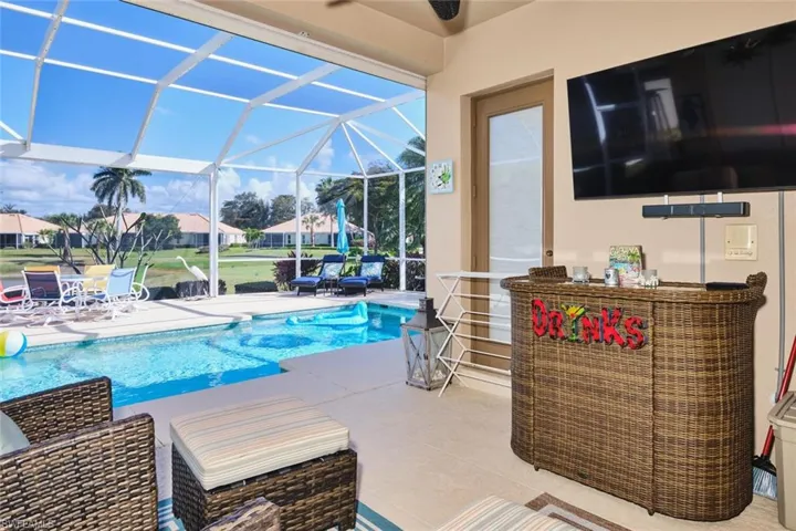 Swimming pool featuring a patio area, a sunroom, glass enclosure, and a residential view