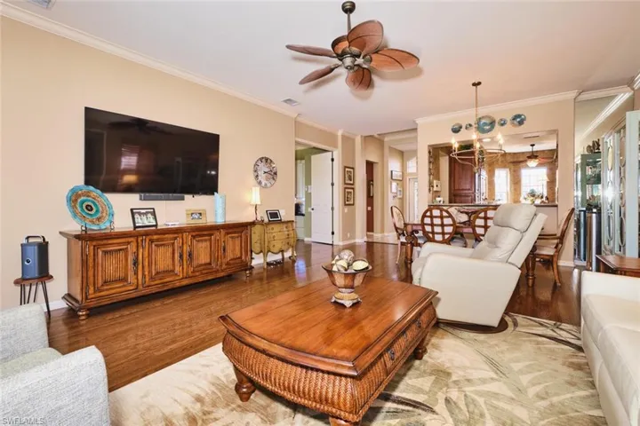Living room featuring ceiling fan, wood finished floors, and crown molding