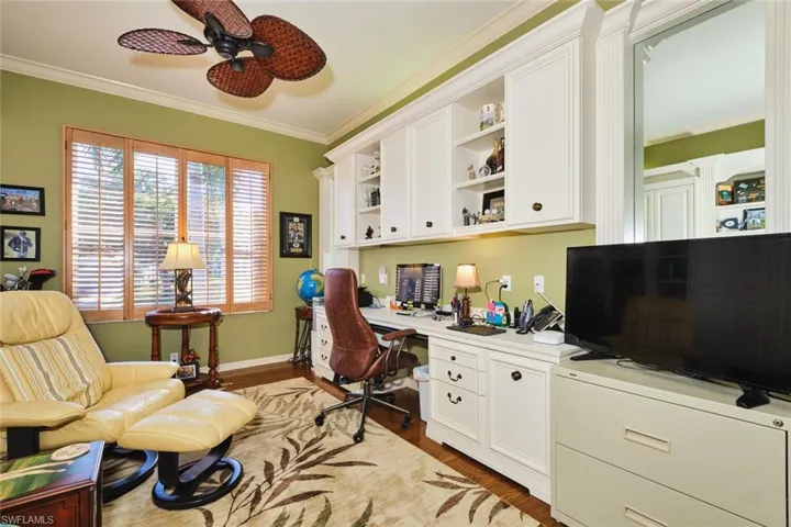 Office space featuring light wood finished floors, ornamental molding, built in study area, and ceiling fan