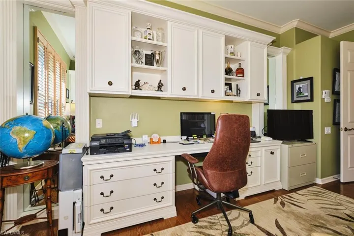 Office space featuring ornamental molding, dark wood-style flooring, and built in desk