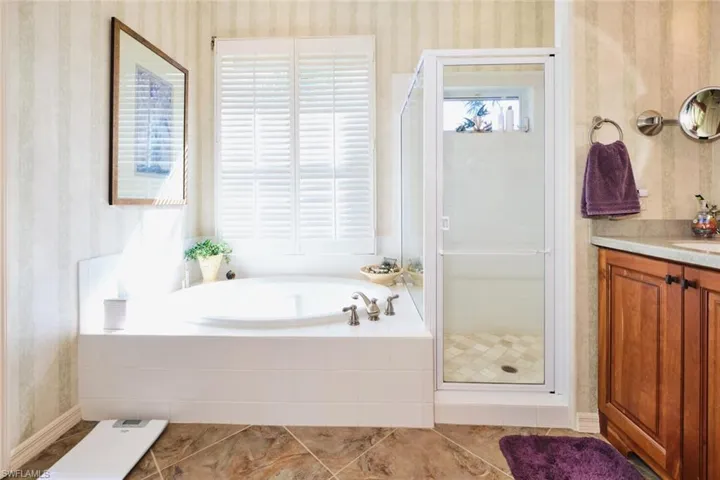 Full bathroom with a shower stall, a garden tub, wallpapered walls, and vanity