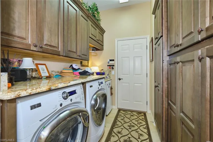 Laundry room with separate washer and dryer, cabinet space, and light tile patterned flooring