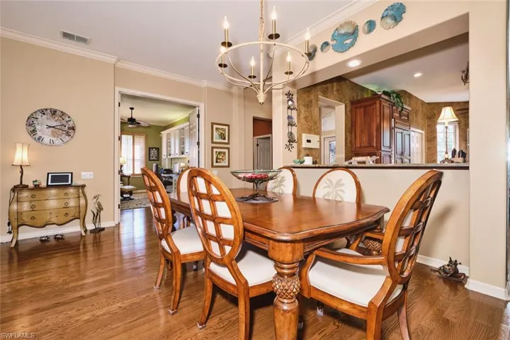 Dining space with hanging lights, ornamental molding, wood finished floors, and ceiling fan