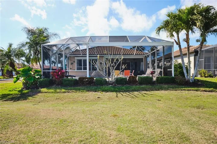 Back of property with glass enclosure, a sunroom, and a lawn