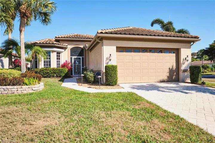 Mediterranean / spanish-style home with stucco siding, driveway, a front yard, and an attached garage