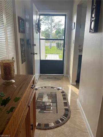 Doorway to outside with marble finish floor, a textured wall, and baseboards