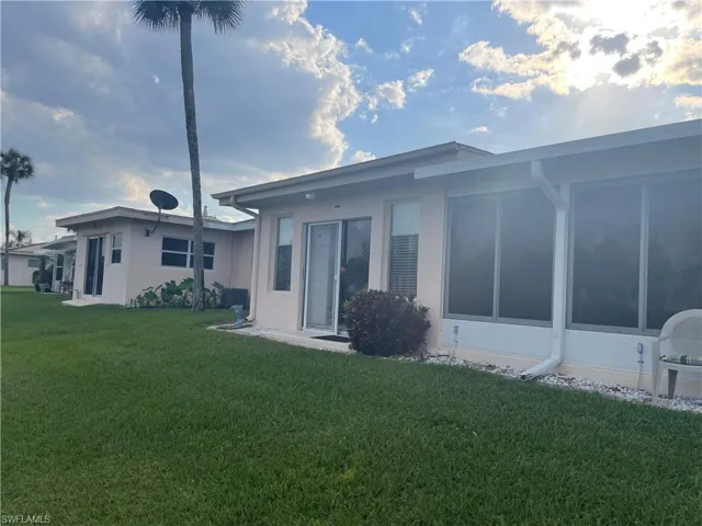 Back of property featuring a lawn and stucco siding