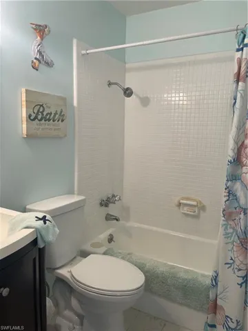 Bathroom featuring toilet, shower / bath combo with shower curtain, and vanity