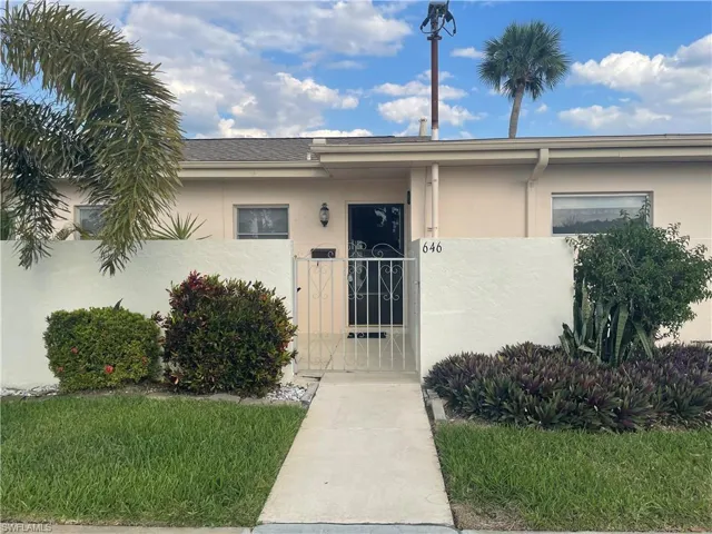 Doorway to property with fence, a gate, and stucco siding