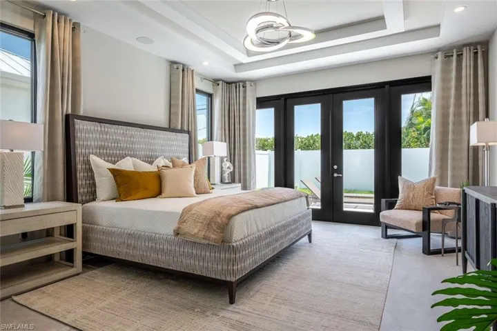 Bedroom with access to outside, french doors, a raised ceiling, and recessed lighting