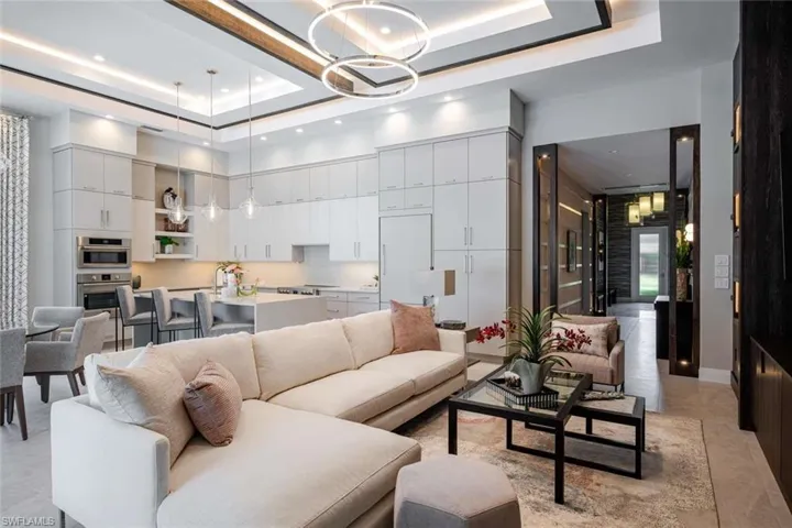 Living room with a raised ceiling, a chandelier, a high ceiling, and recessed lighting