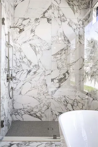 Full bath featuring a marble finish shower, a freestanding tub, and marble finish flooring