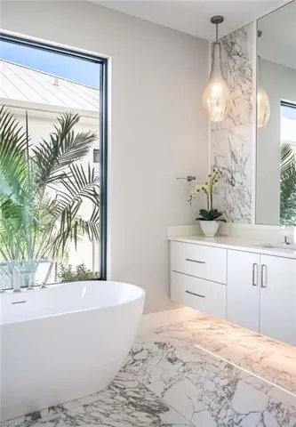 Bathroom with vanity, a freestanding bath, and marble finish flooring