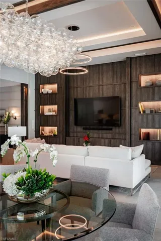 Living room with a chandelier, wooden walls, and a raised ceiling