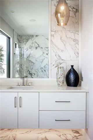 Full bathroom featuring marble finish floors, vanity, and a marble finish shower