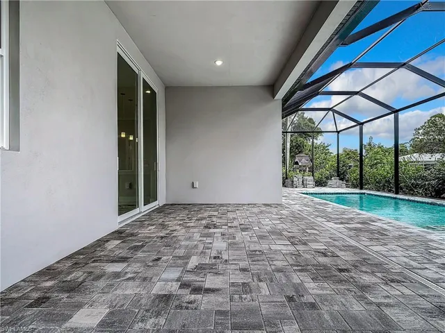 View of swimming pool with glass enclosure and a patio area