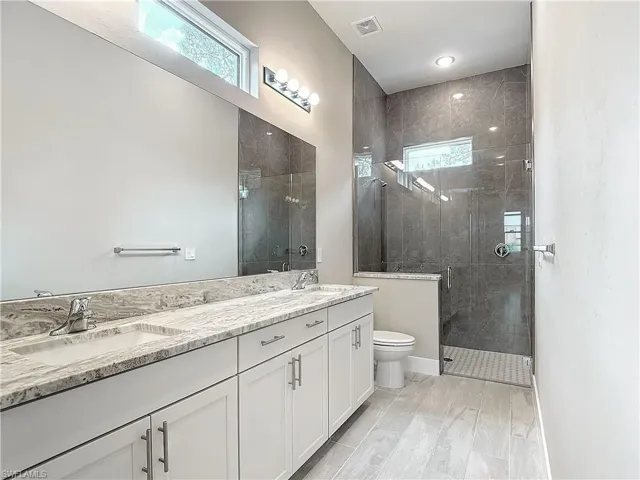 Bathroom with wood-type flooring, walk in shower, vanity, and toilet