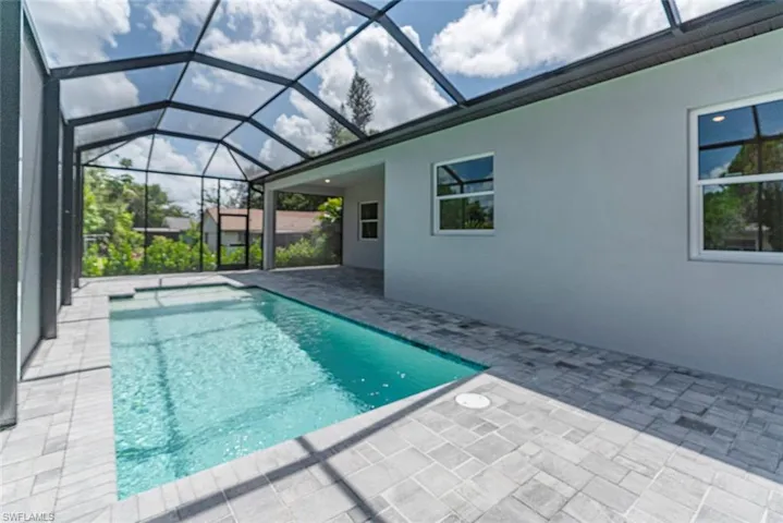 View of swimming pool with glass enclosure and a patio area