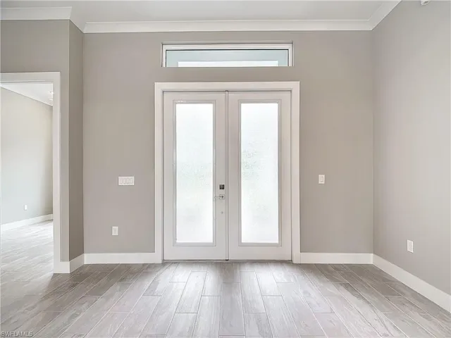 Doorway to outside featuring light wood-type flooring, french doors, and crown molding