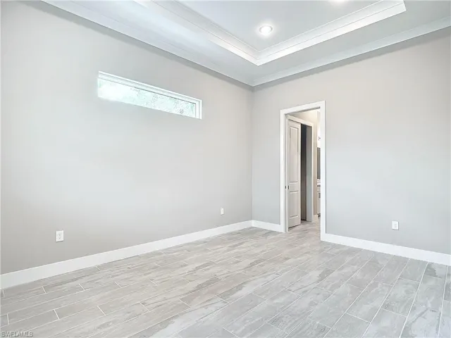 Spare room featuring ornamental molding, a raised ceiling, and light hardwood / wood-style flooring