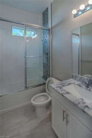Full bathroom with vanity, enclosed tub / shower combo, and toilet