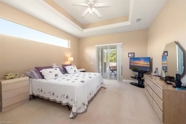 THe primary bedroom has a tray ceiling and a slider to the pool deck area.