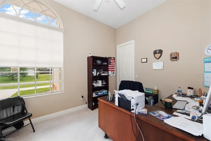This home office has a front view window and a door that connects to the master bath.