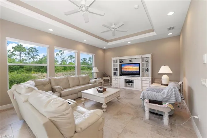 The family room features a tray ceiling with a triple window of the nature preserve as well as sliders to the pool deck area.