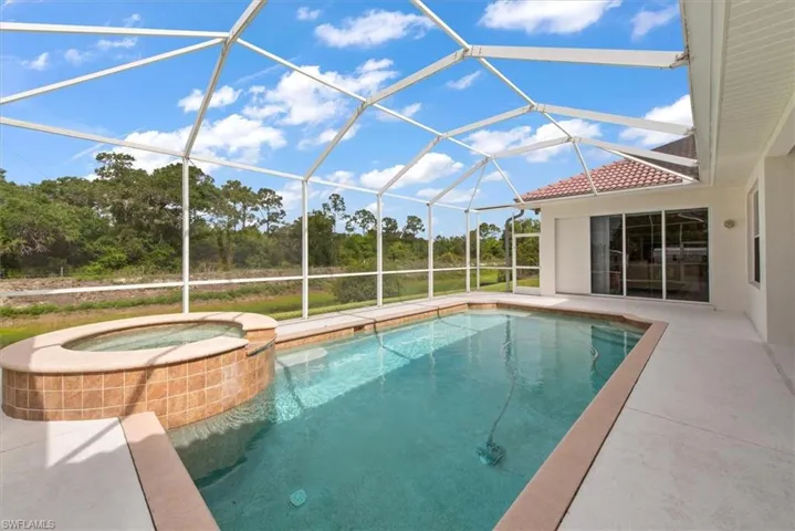 Pool view from the  left end. There is an outdoor shower just outside the screened door. in the background.