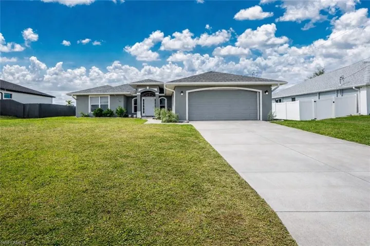 Ranch-style house featuring an attached garage, stucco siding, and driveway