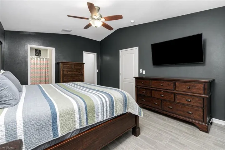 Bedroom featuring ceiling fan, lofted ceiling, and wood tiled floors
