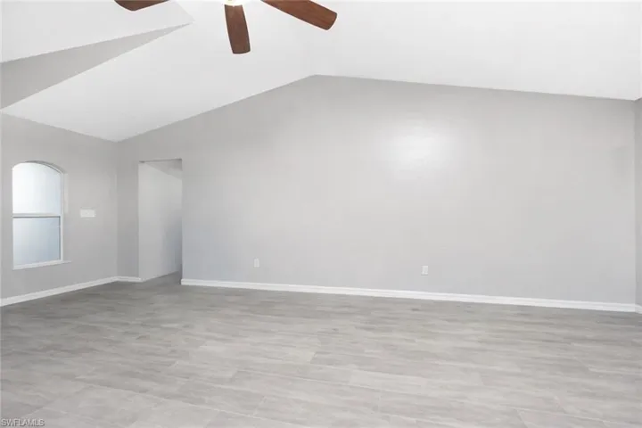 Empty room featuring lofted ceiling and ceiling fan