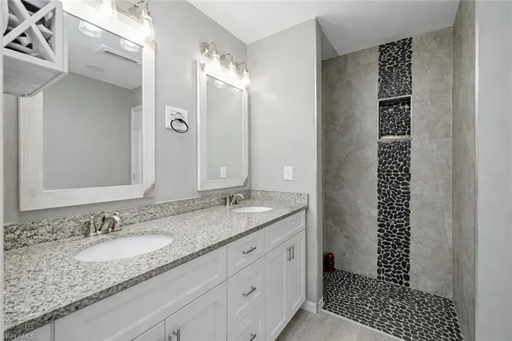 Bathroom featuring a walk in shower and double vanity
