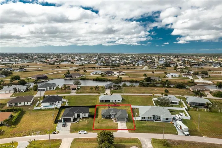 Aerial perspective of suburban area featuring property boundaries highlighted and a nearby body of water