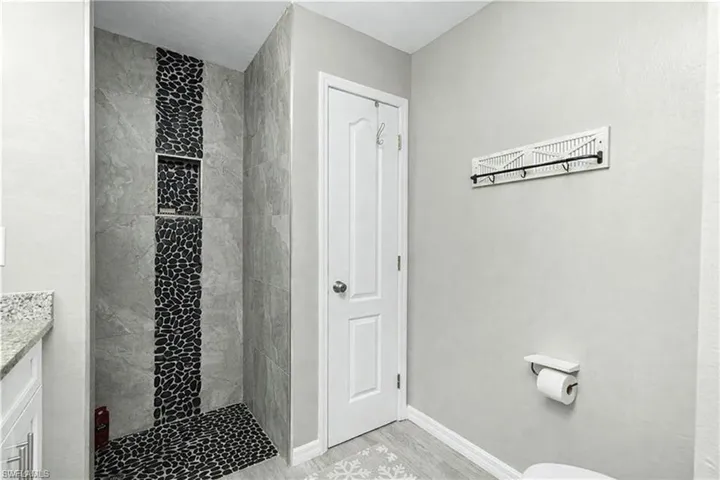 Full bathroom with a stall shower, vanity, and light wood finished floors